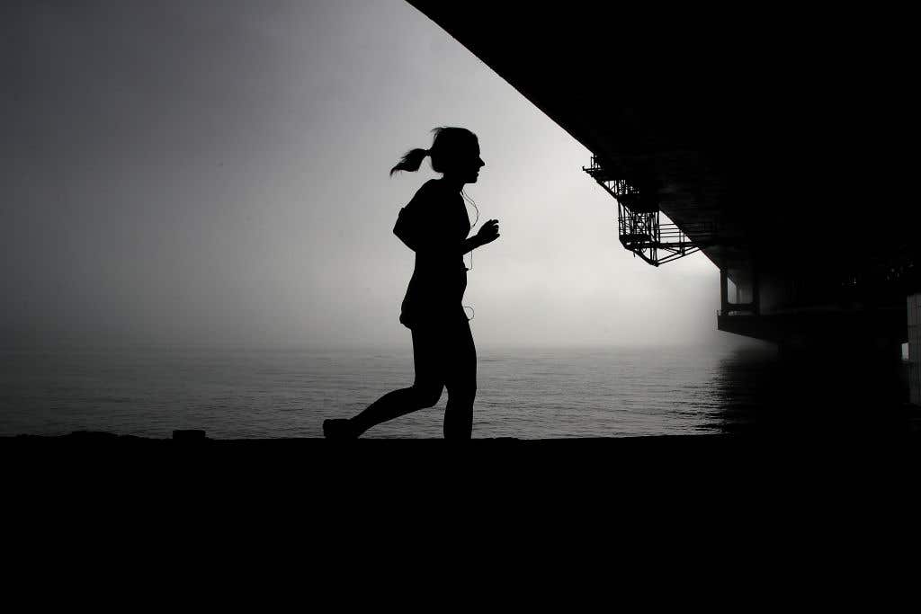 A morning jogger runs underneath Auckland Harbour Bridge as fog drifts