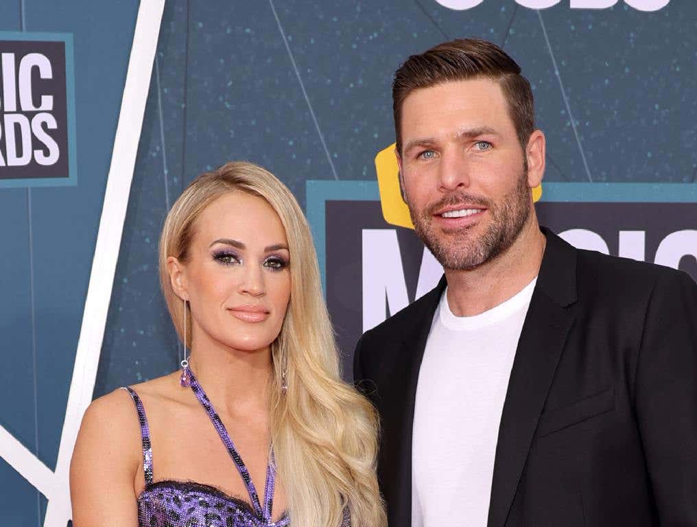 Carrie Underwood in a purple dress and husband Mike Fisher in a blue jacket and white t-shirt