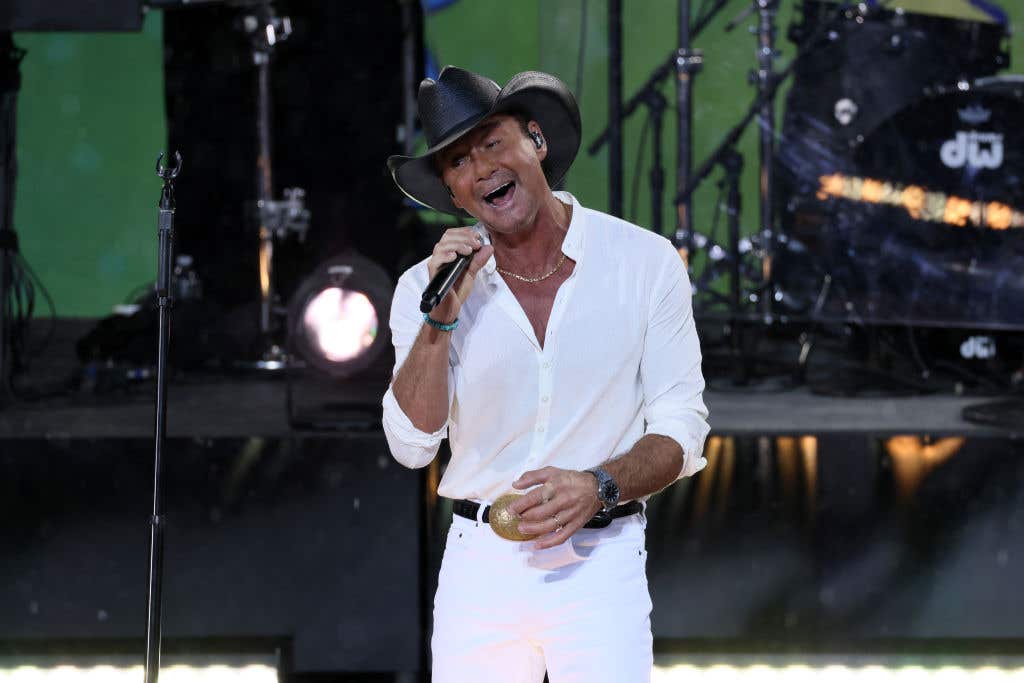 Tim McGraw wearing white (but a black hat) performing on stage