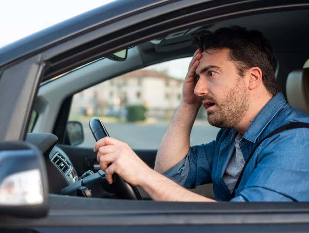 Man driving with confused face and hand on head, zoning out driving concept.