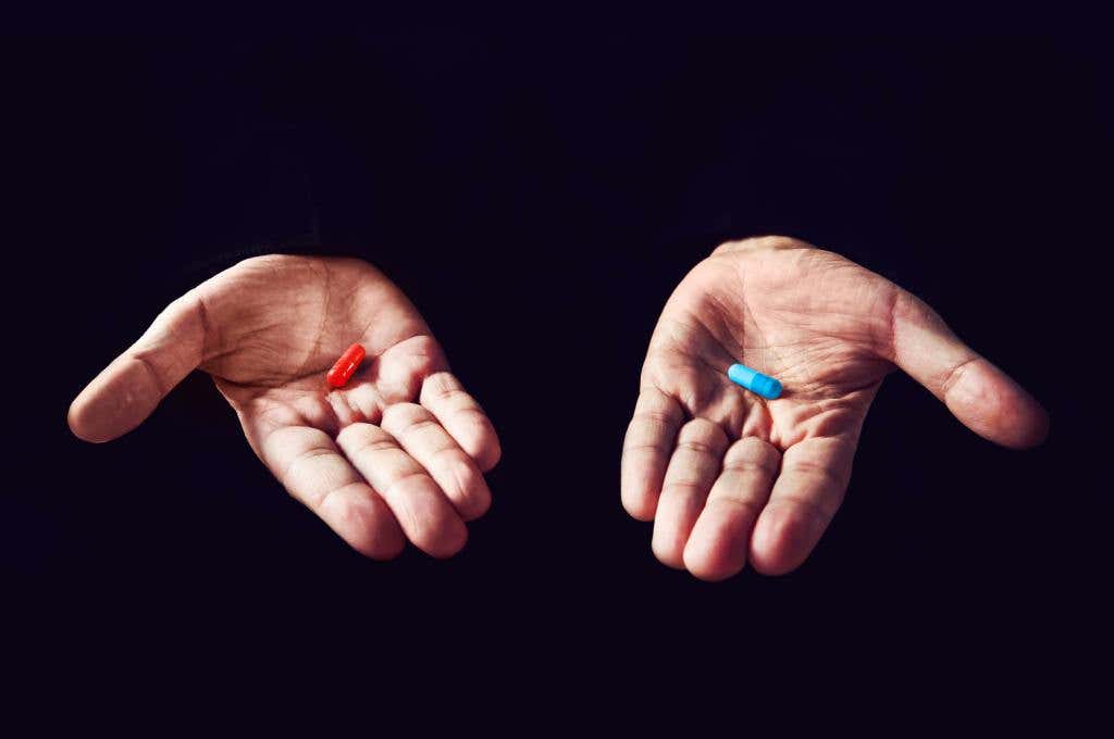 hands holding a red pill and a blue pill