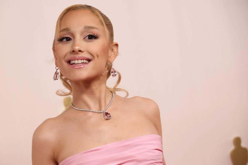 Ariana Grande attends the 96th Annual Academy Awards smiling wearing a pink dress for our worst dress oscars red carpet list.