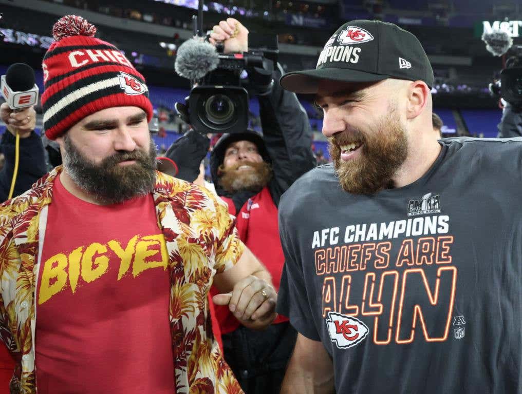 Jason Kelce in a red shirt and hat, and Travis Kelce in a black shirt and hat.