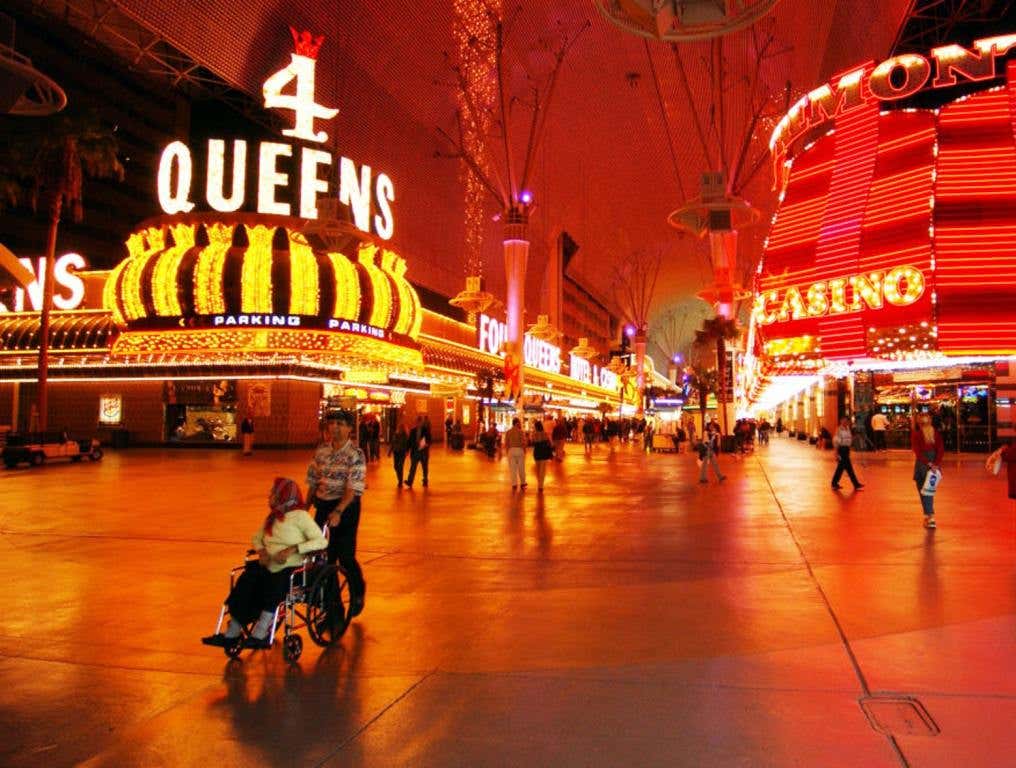 The Four Queens Hotel & Casino is getting a $24 million dollar renovation to its North Tower. Street-view photo from November 2002 of Fremont Street Experience. The entire photo has a reddish tint to it. The 4 Queens neon sign can be seen on the left. The Fremont Casino's neon sign can be seen on the right side of the photo. There are people milling about on the Fremont Street Experience.