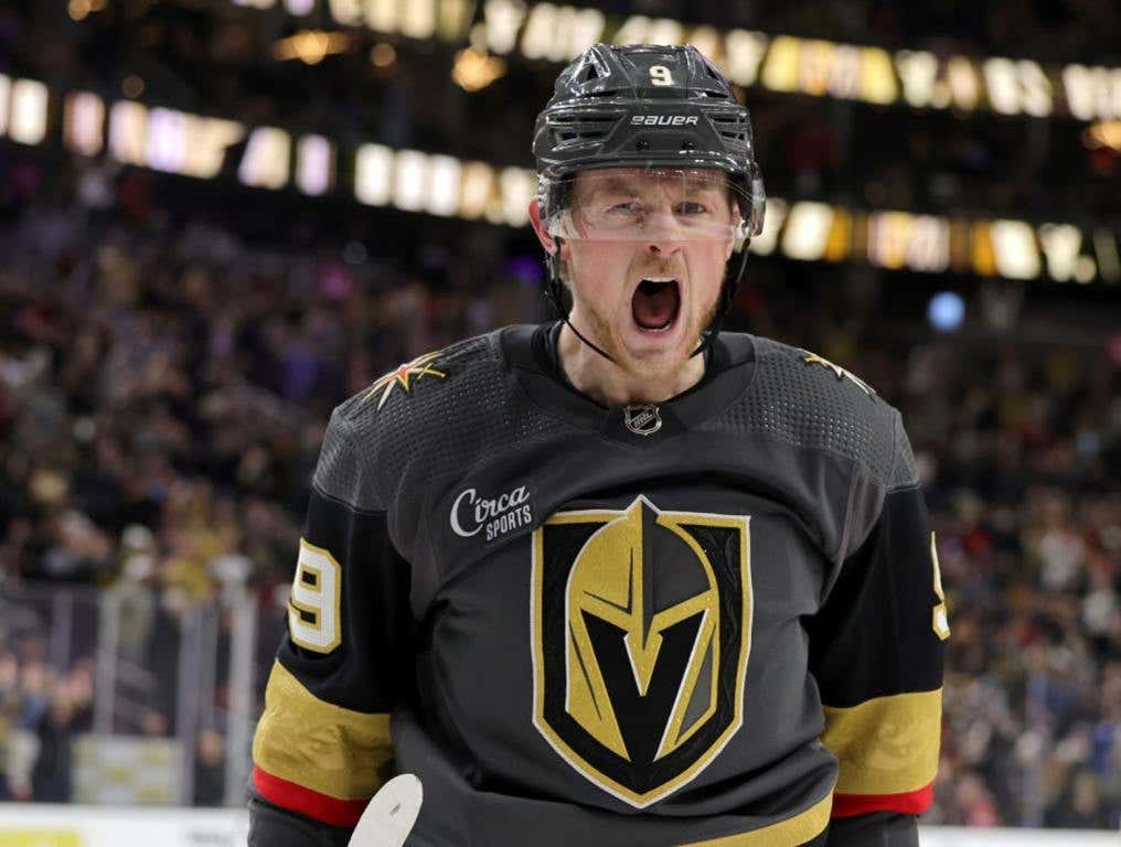 Battle for Vegas charity softball game features Team Eichel vs Team Cole. Photo of Vegas Golden Knights forward Jack Eichel, #9, screaming with excitement after scoring a goal in a game against the Carolina Hurricanes at T-Mobile Arena in Las Vegas on March 1, 2023. It is a close-up photo of Eichel which includes his torso, shoulders and head. He is wearing the Vegas Golden Knights home gray jersey and helmet.