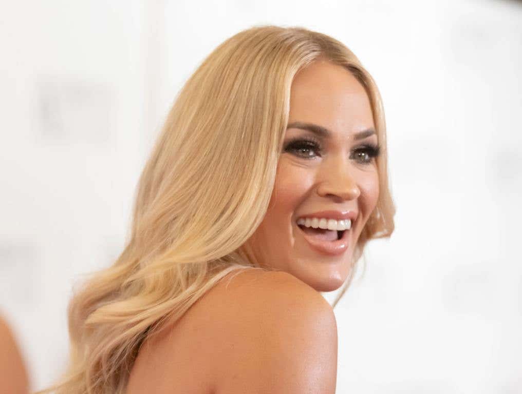 Carrie Underwood is smiling on a red carpet.