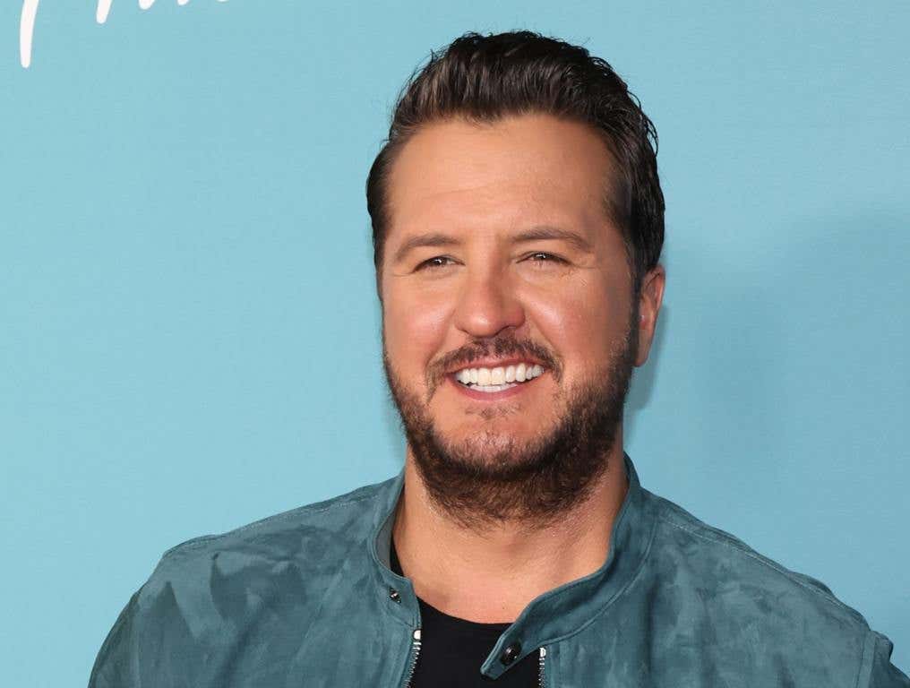 Luke Bryan posing in a denim jacket and black shirt.