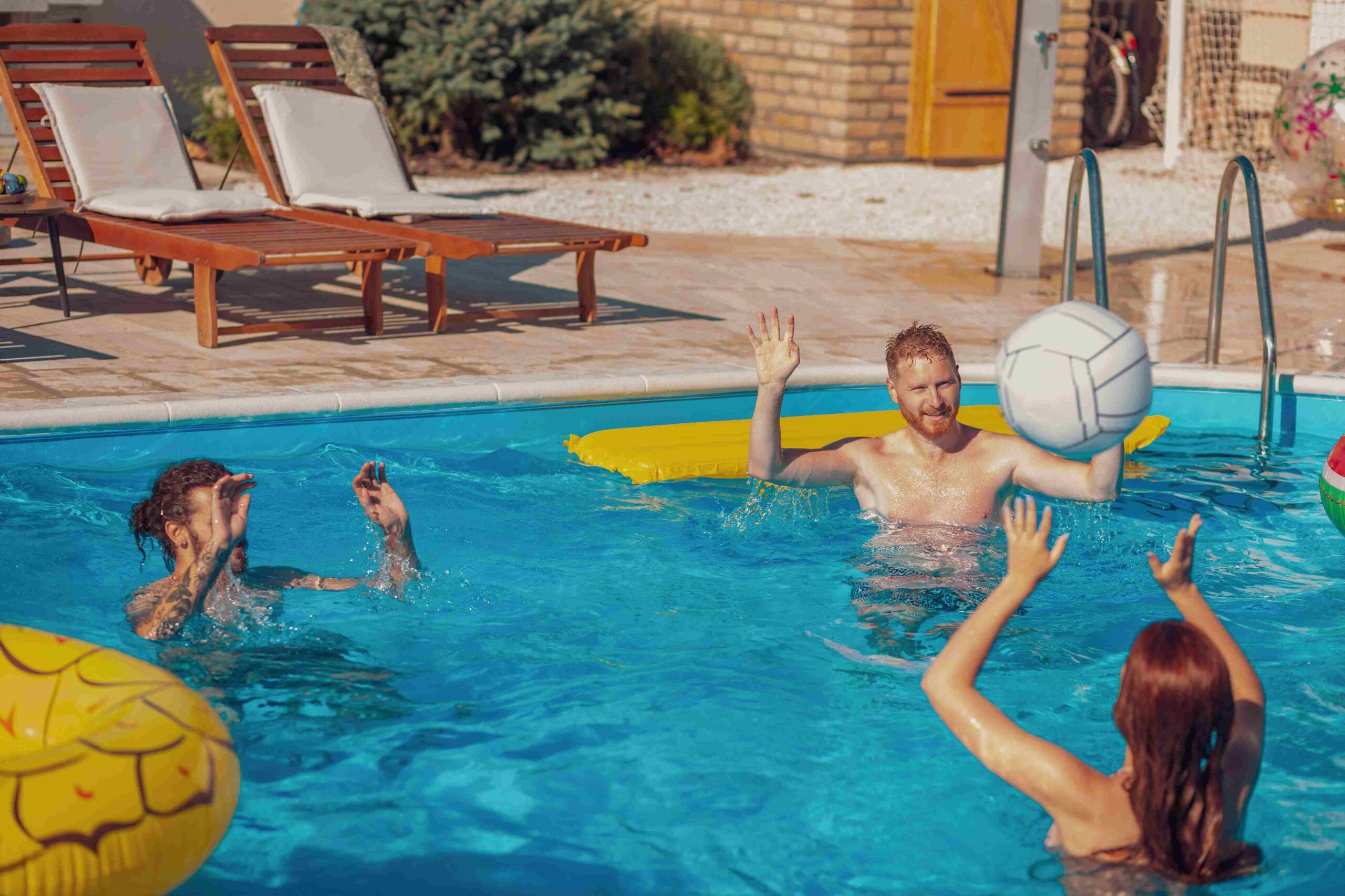 Three people playing pool volleyball