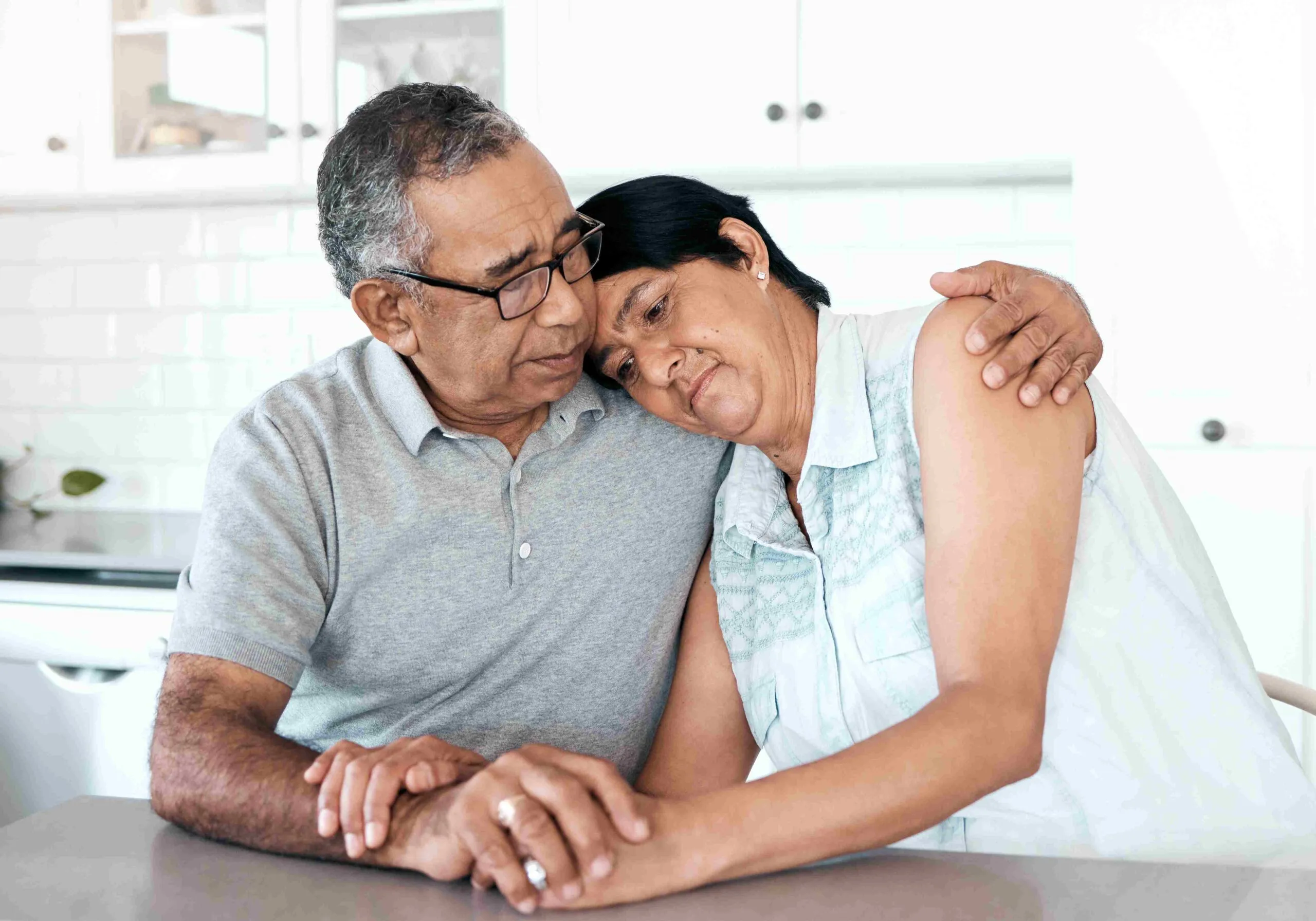 Elderly couple looking sad with wife in her husband's arms